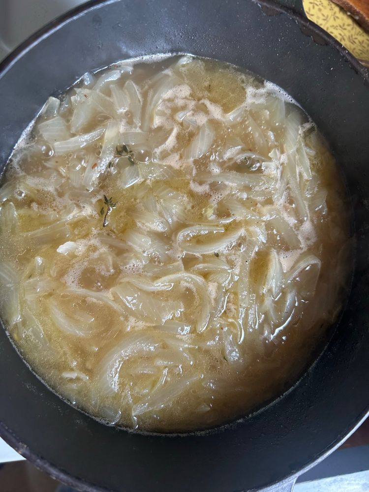 a pot of simmering golden brown french onion soup 