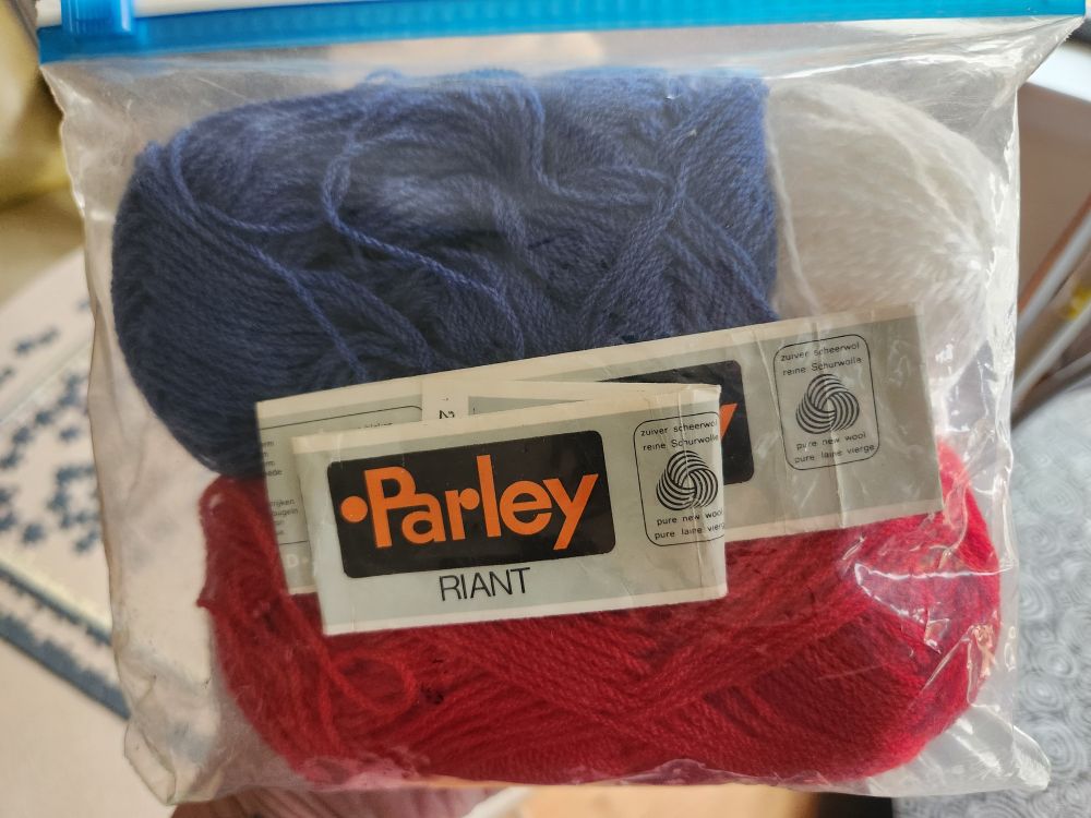 A ziploc bag with red, blue and white yarn and their older Parley labels, indicating it's virgin wool 
