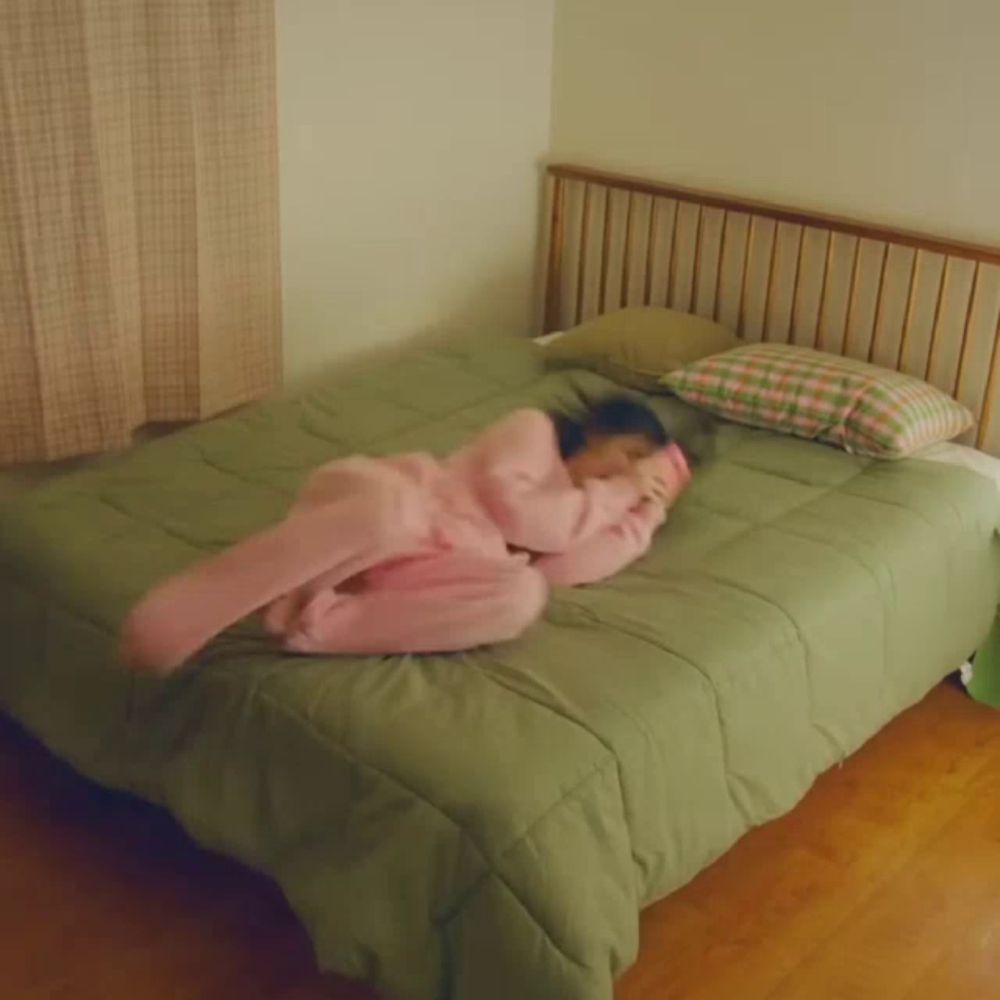 a person in pink pajamas is laying on a bed