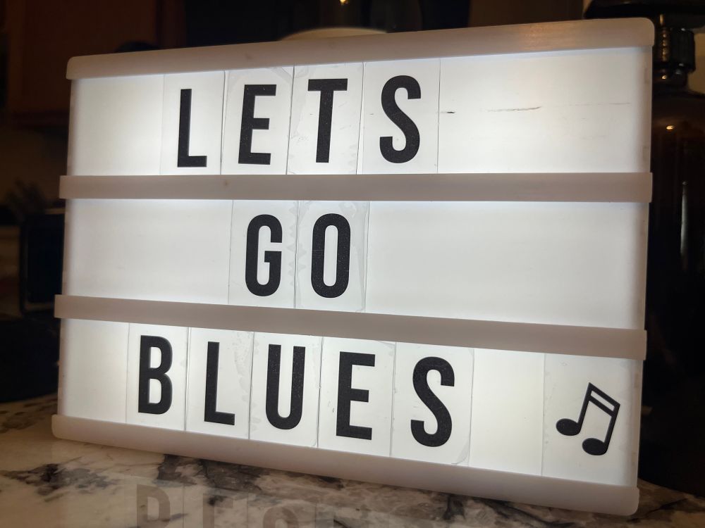 A back lit sign that reads “Let’s Go Blues”

