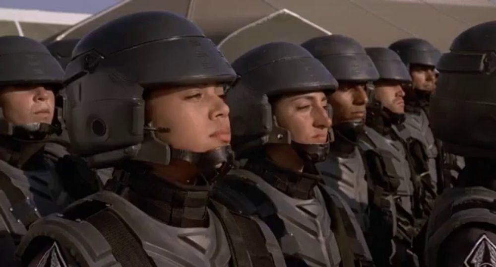 a group of soldiers are standing in a line with their eyes closed and their helmets on