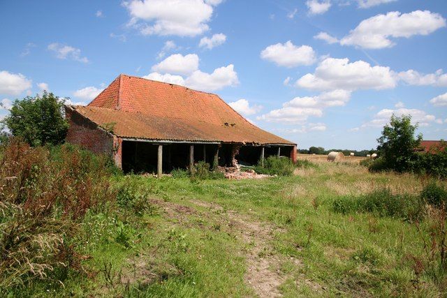 A mud and stud barn in 2007. Pan tiled roof and seven bay open cart shed to the side. A beautiful day in summer, with harvested wheat field behind