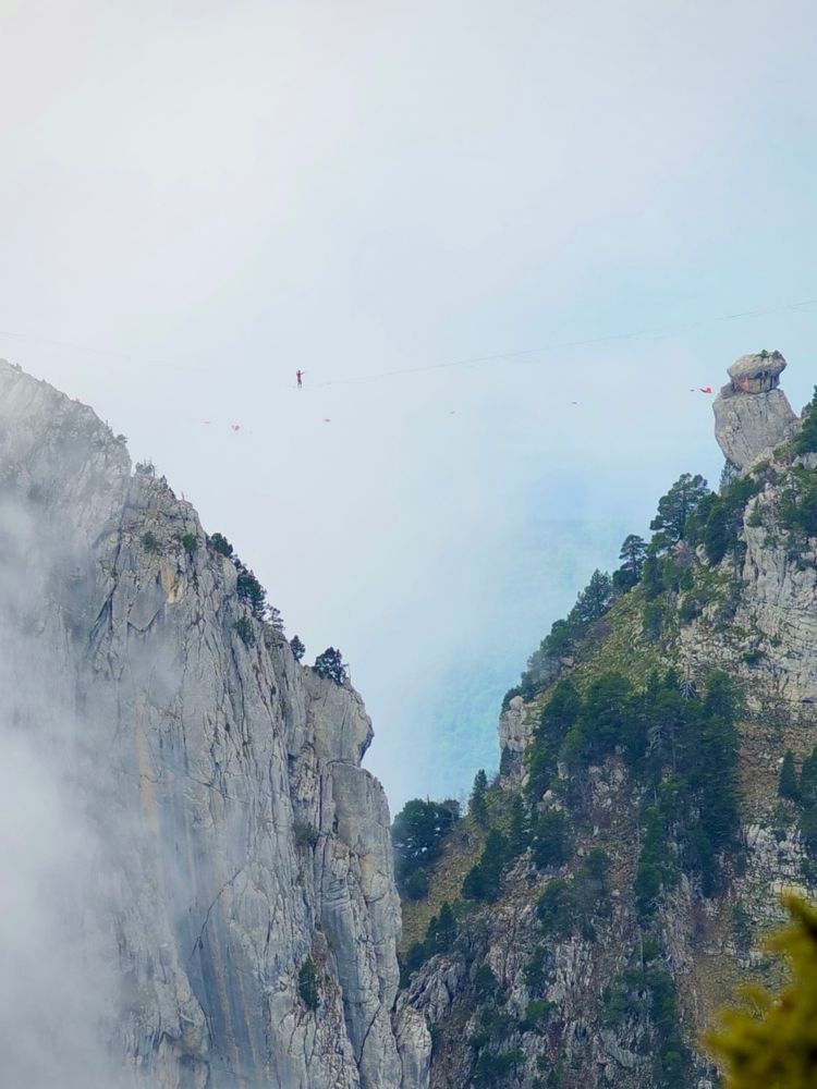 a climber balances on a rope between two mountains