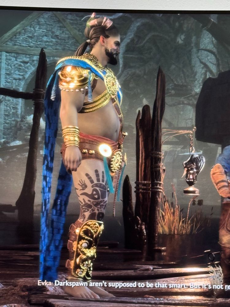 A video game character wearing a harness cape that is gold with short shorts and shin guards
