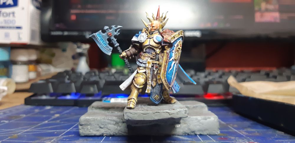 mini de chez games worshop, un homme dans une armure d'or se tient sur un rebord le regard au loin 
vue de face