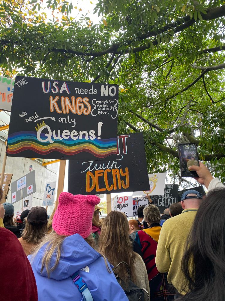 Many protest signs, “the USA needs no kings we need only Queens”