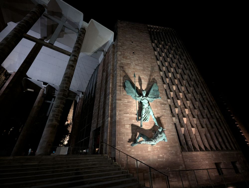 Coventry Cathedral exterior with Holy Trinity spire in background.