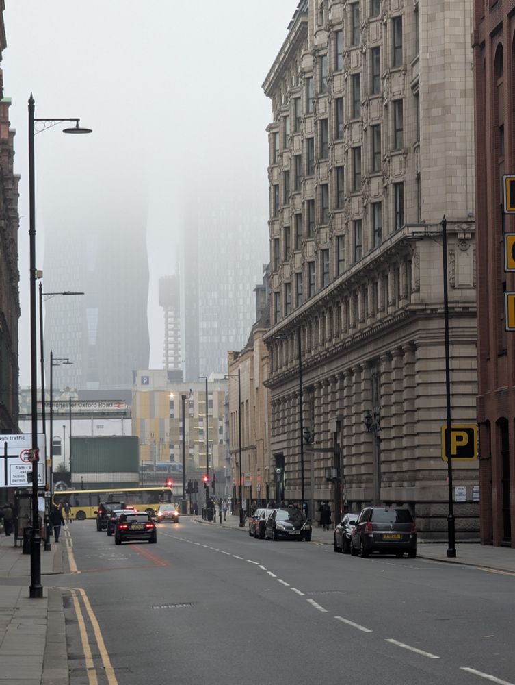 Street scene in a foggy Manchester. Tower blocks disappear into the mist.
