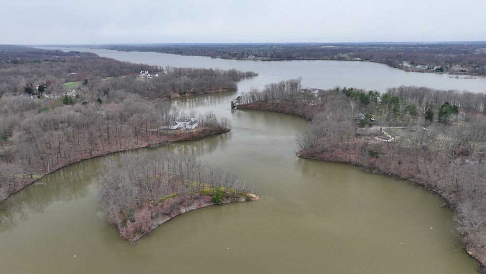 A lake with an island. There are large houses on the shore