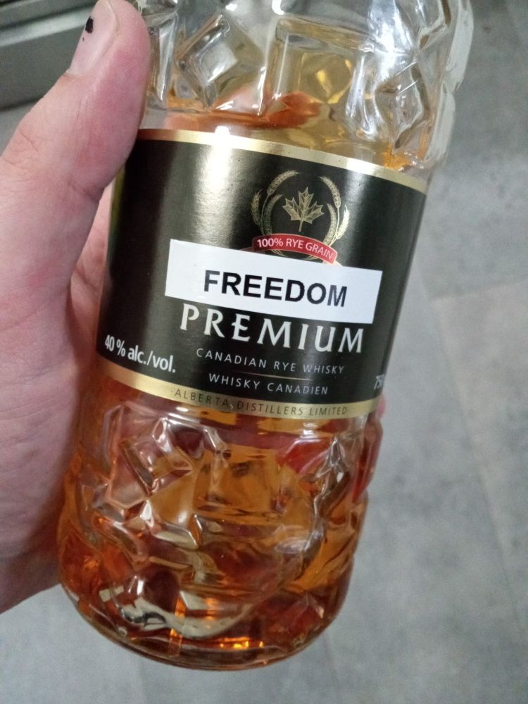 A bottle of Alberta Premium brand rye whiskey with a printed label reading FREEDOM covering the word Alberta
