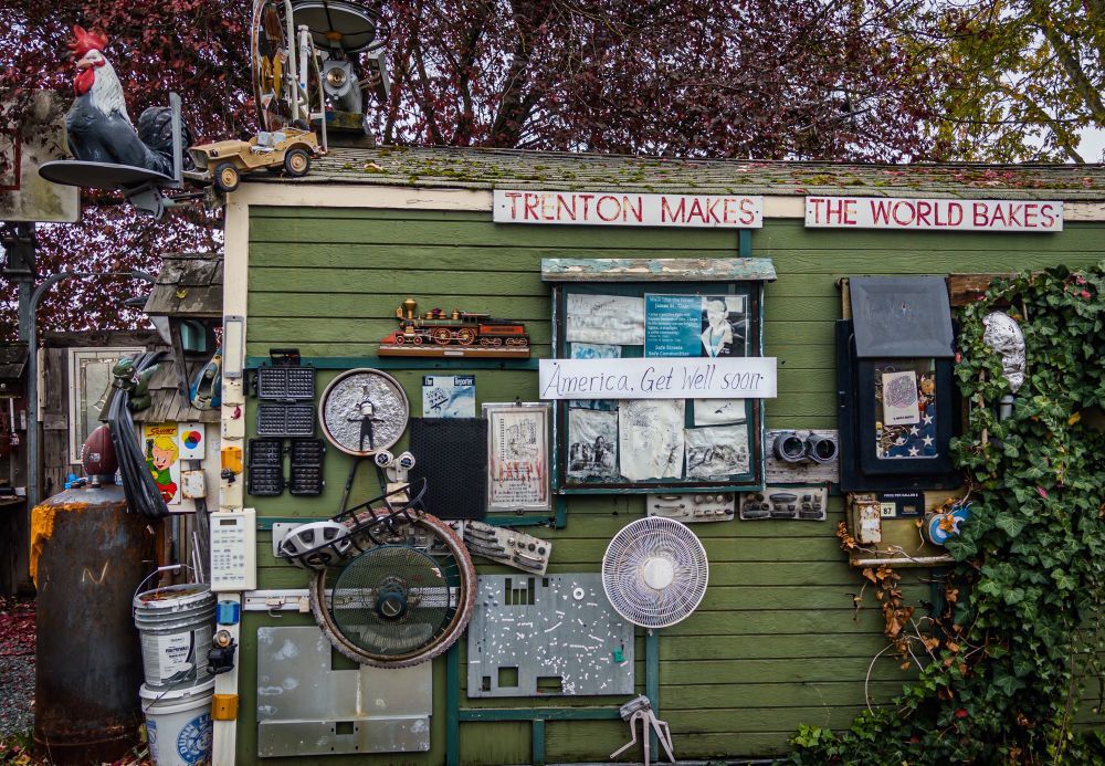An exterior garage wall adorned with a bunch of stuff, including a sign that says "America, Get Well Soon"