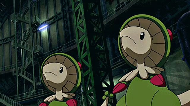 two green and brown cartoon characters are standing next to each other in front of a building