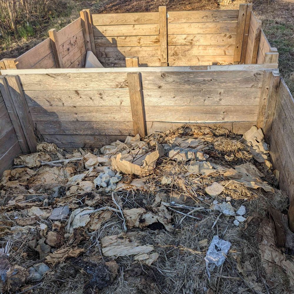 Two large compost bins, one in front of the other. The front one is filled with unfinished compost.