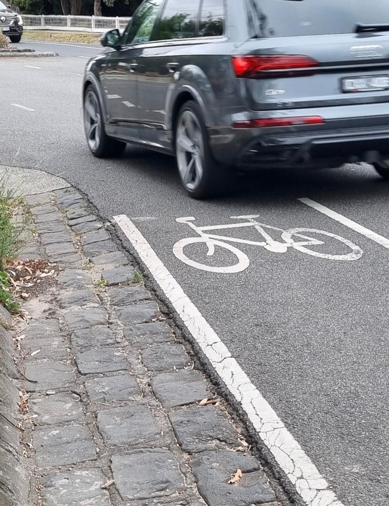 Car driver cutting dangerously into unprotected bike lane, jeopardising cyclist's safety