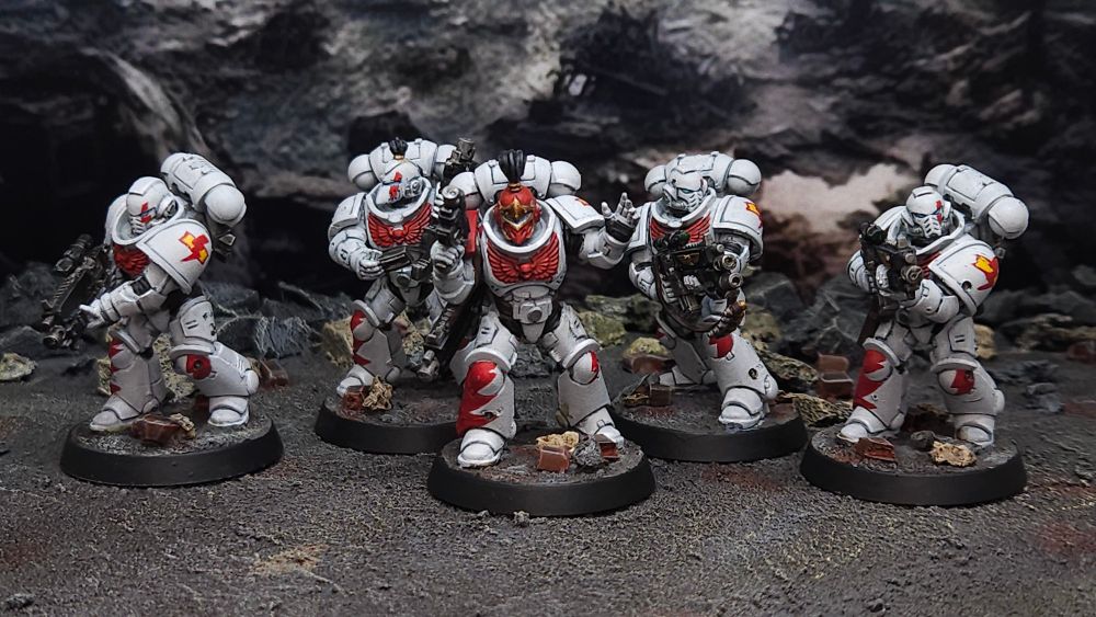A squad of White Scars space marines in white and red armor posed on an urban rubble backdrop. 