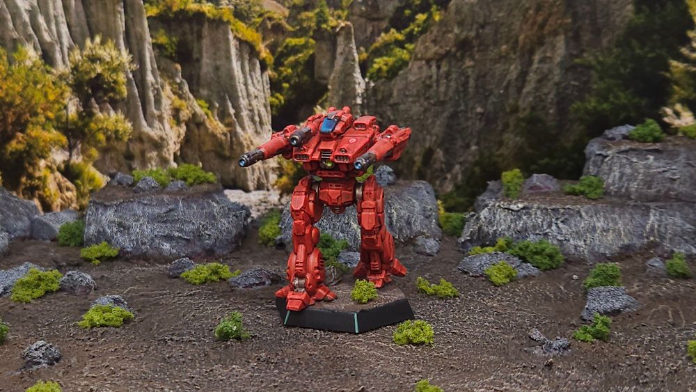 A Lancelot battlemech miniature painted in bright red Sword of Light coloes posed on a scrublands backdrop.