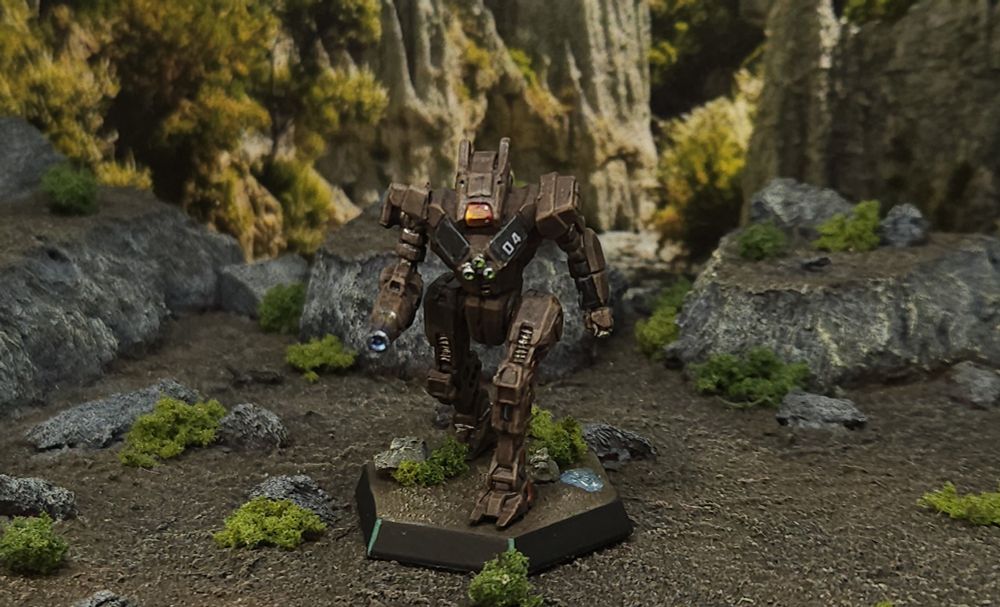 A Wolfhound battlemech miniature painted in brown and black Taurian colors posed on a scrubland backdrop. 