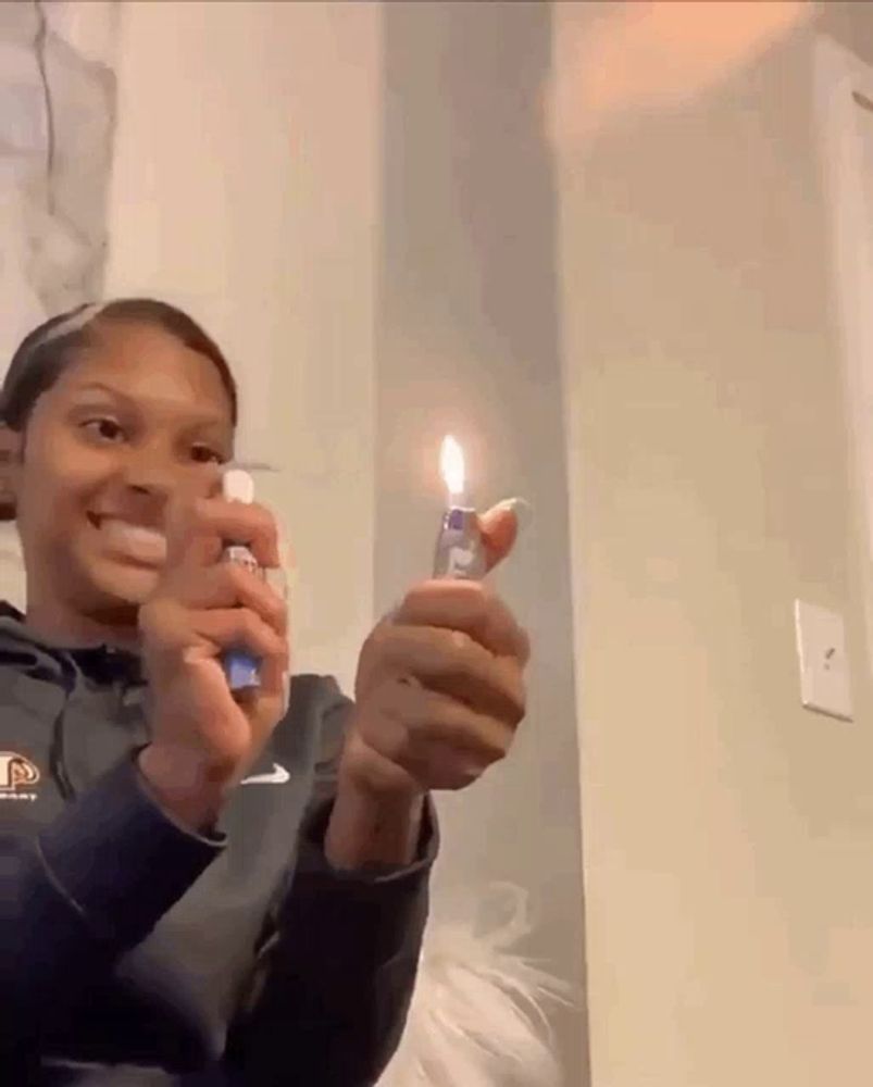 a person is holding a lighter in their hand and smiling