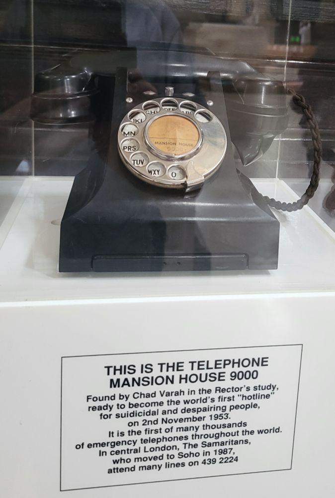 Ein altes Wählscheiben-Telefon in einer Glasvitrine. Unten englische Beschriftung 