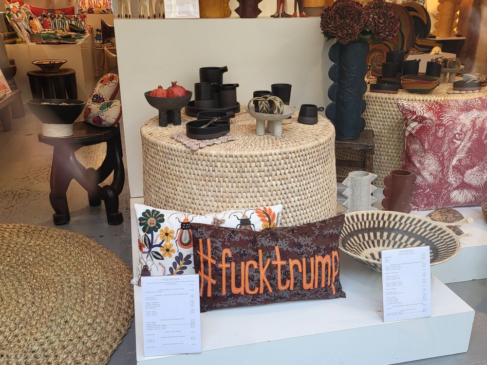 Schaufenster eines Einrichtungsladens mit einem Kissen, auf dem in orangner Schrift groß der Hastag "#fucktrump" steht.
