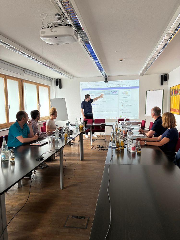 Besprechungsraum: Am Ende das LinkedIn Profil vom VAA mit dem Beamer auf die Wand geworfen – Christian Dietz zeigt etwas darauf. Links: Christian Lange, Ilhan Akkus und Luisa Reim schauen nach vorn. Gegenüber: Ina Brocksieper und Stephan Gilow. Foto: VAA