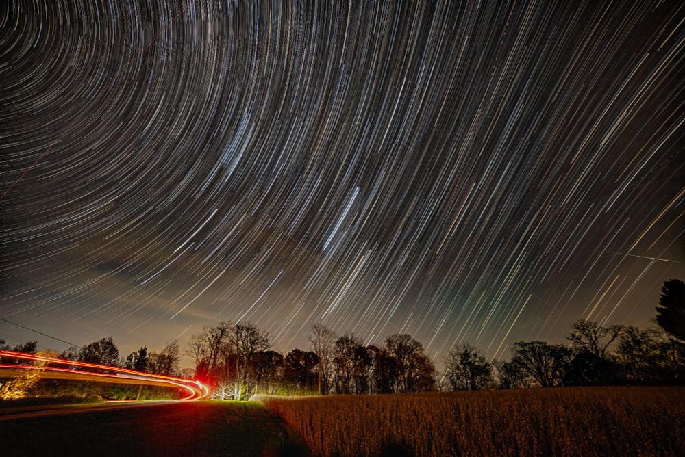 A star trail photo looking east. On the left, the stars cure to the left around the north star. On the right, the stars curve to the right around the south pole.