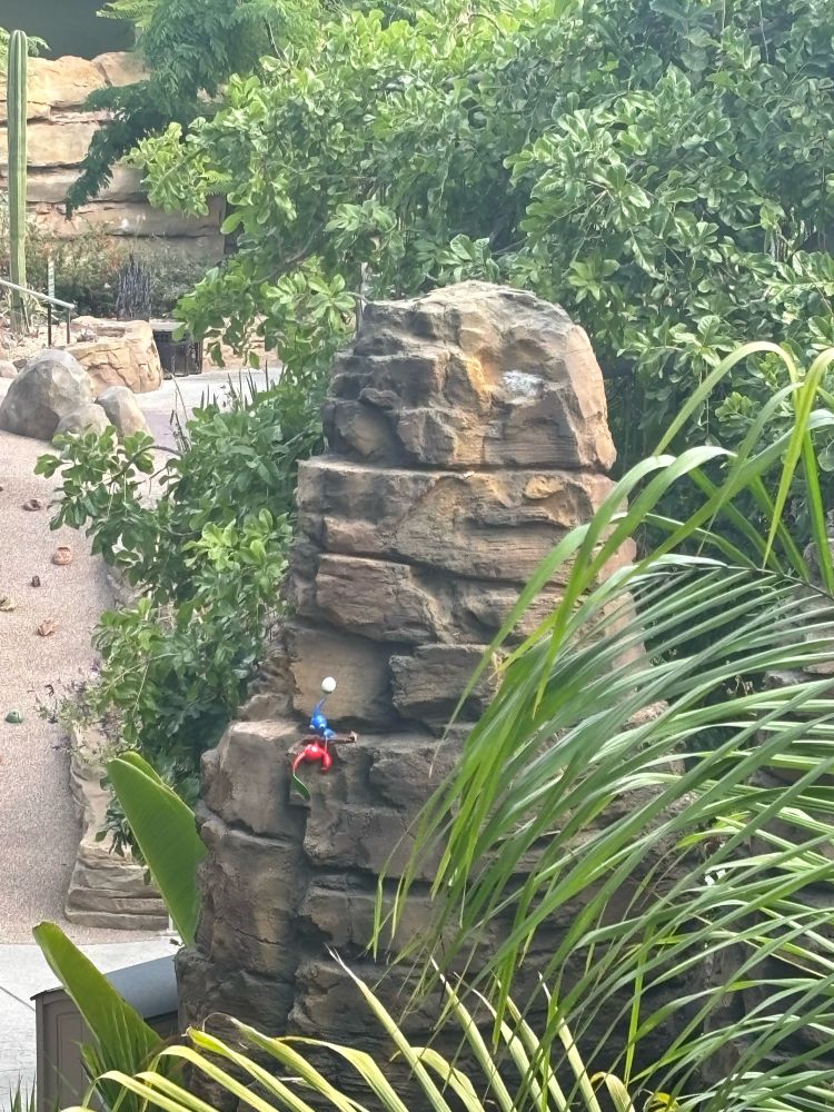 A pikmin is being helped by another to prevent it from falling off a cliff