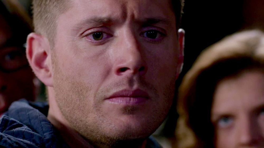 Dean looking down at the angel blade Hannah has given Cas, Stairway to Heaven. An angel looks on in the background. 