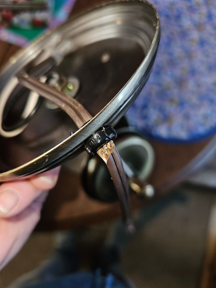 A small brass lamp base showing broken wires caused by faulty workmanship at the factory 