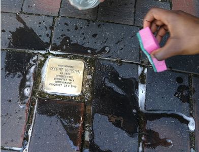 Ein Stoplerstein wird gerade geputzt & strahlt schon wieder mit lesbarer Information