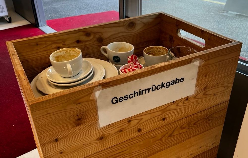 A wooden box in a cafe in Zurich with the label 'Geschirrrückgabe' intended to hold used cups and plates 