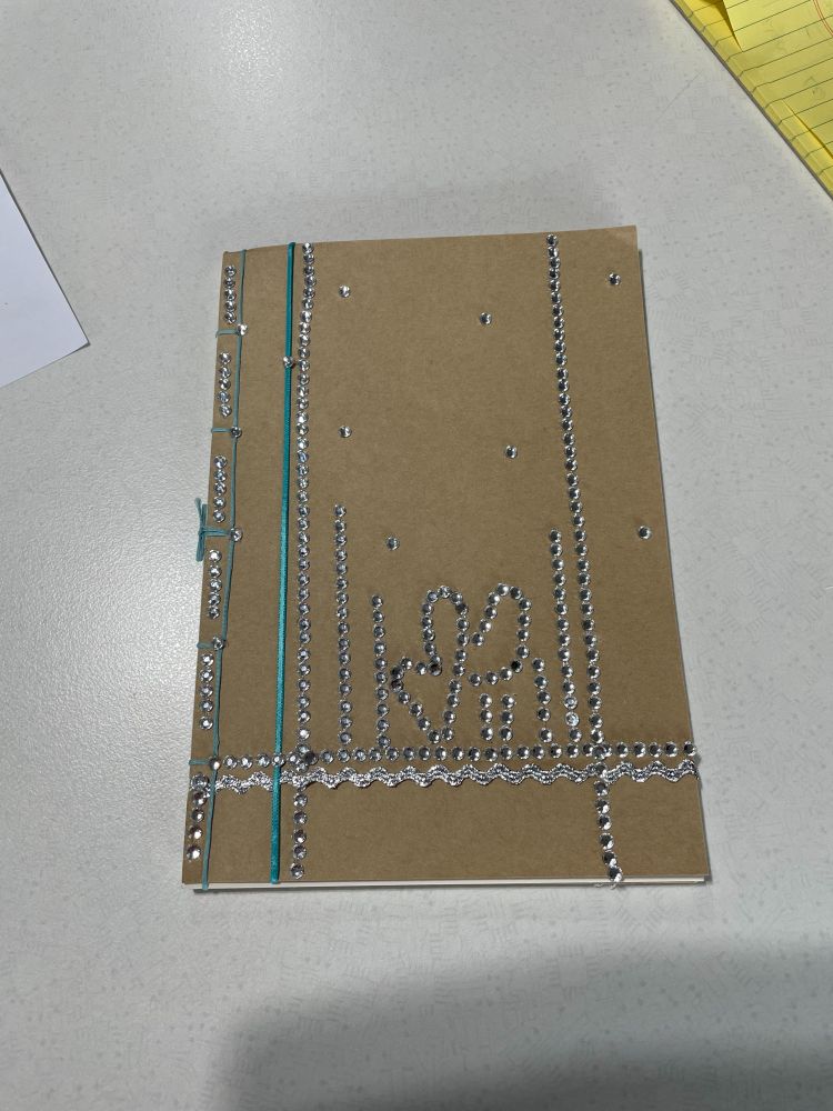 Thread-bound notebook with light blue thread binding and bedazzled cover.