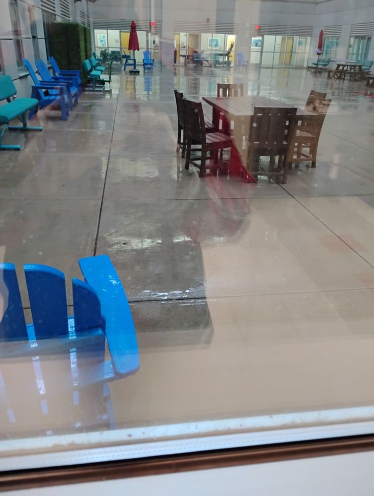 Rain in the Muskogee VA Hospital courtyard. Brown & blue chairs & tables are wet.