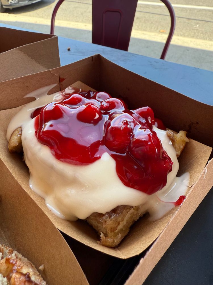 Cinnamon roll with cream and cherries