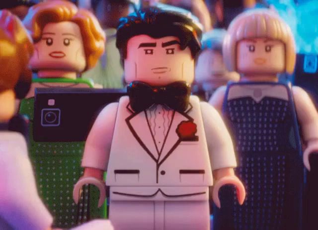 a lego man in a tuxedo and bow tie is standing in a crowd of people