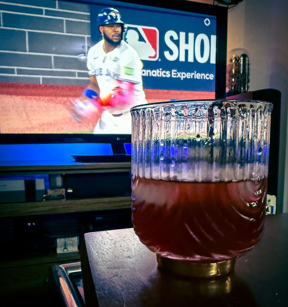 A cocktail in the foreground with the World Series on a TV in the background