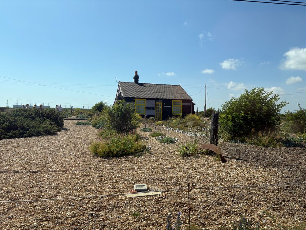 Derek Jarman’s fisherman cottage with bright yellow windows and greenery 
