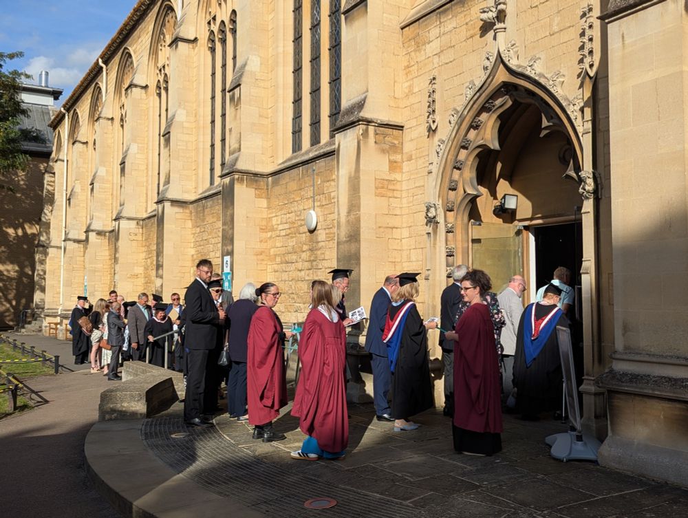 Graduates and guests gathered outside the historic stone chapel at Francis Close Hall with Gothic architecture. People in academic regalia and formal attire line up to enter, bathed in warm late-afternoon sunlight that highlights the building’s detailed stonework.