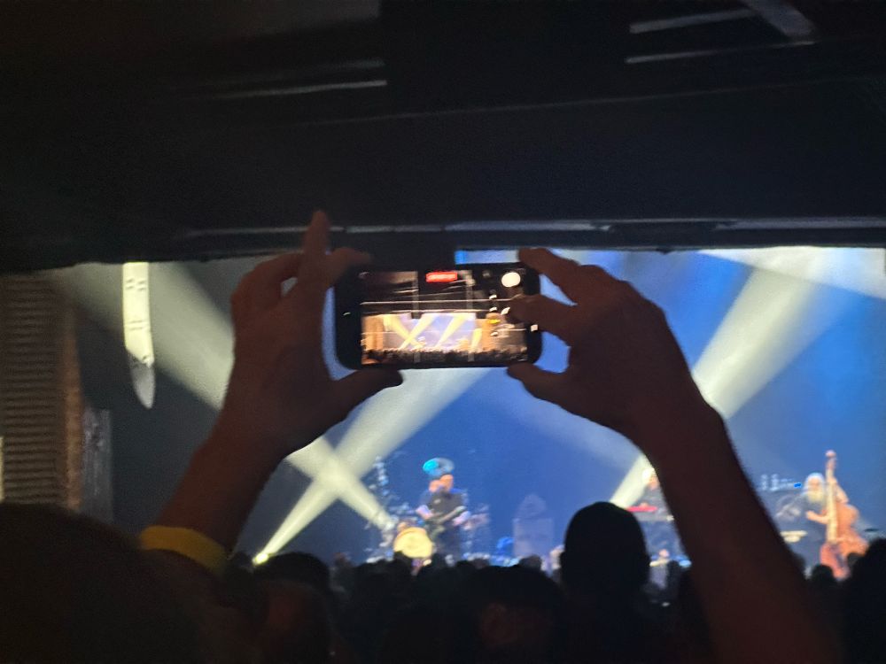 A cellphone picture of someone taking a cellphone picture of the stage at a concert. 