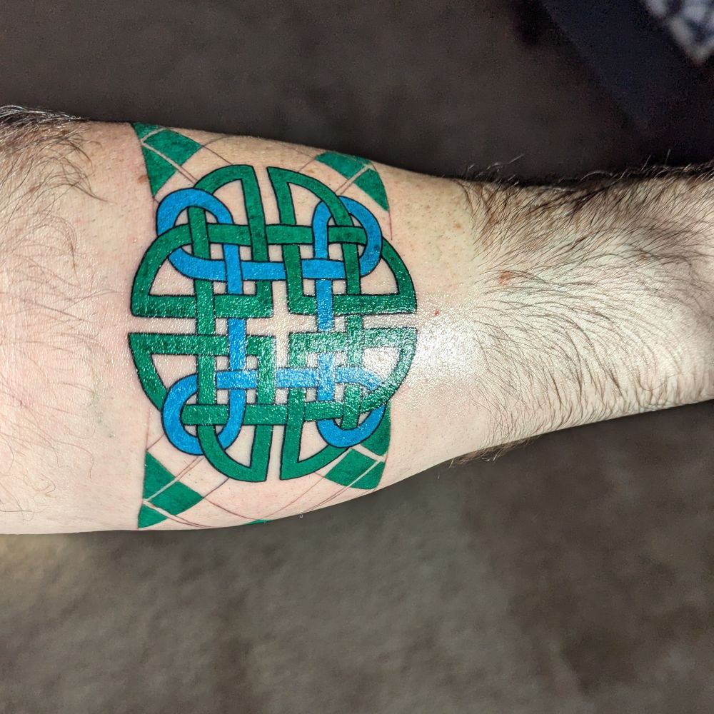Arm band tattoo: Dara knot in blue and green with the beginning of the Welsh Jones tartan
