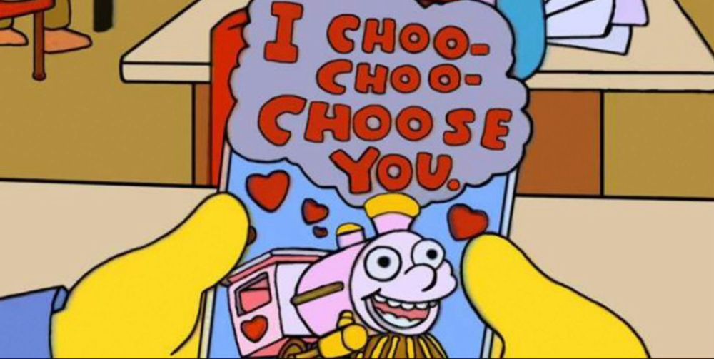 Scene from the simpsons showing a Valentine’s Day card that is train themed and has the text “i choo choo choose you”