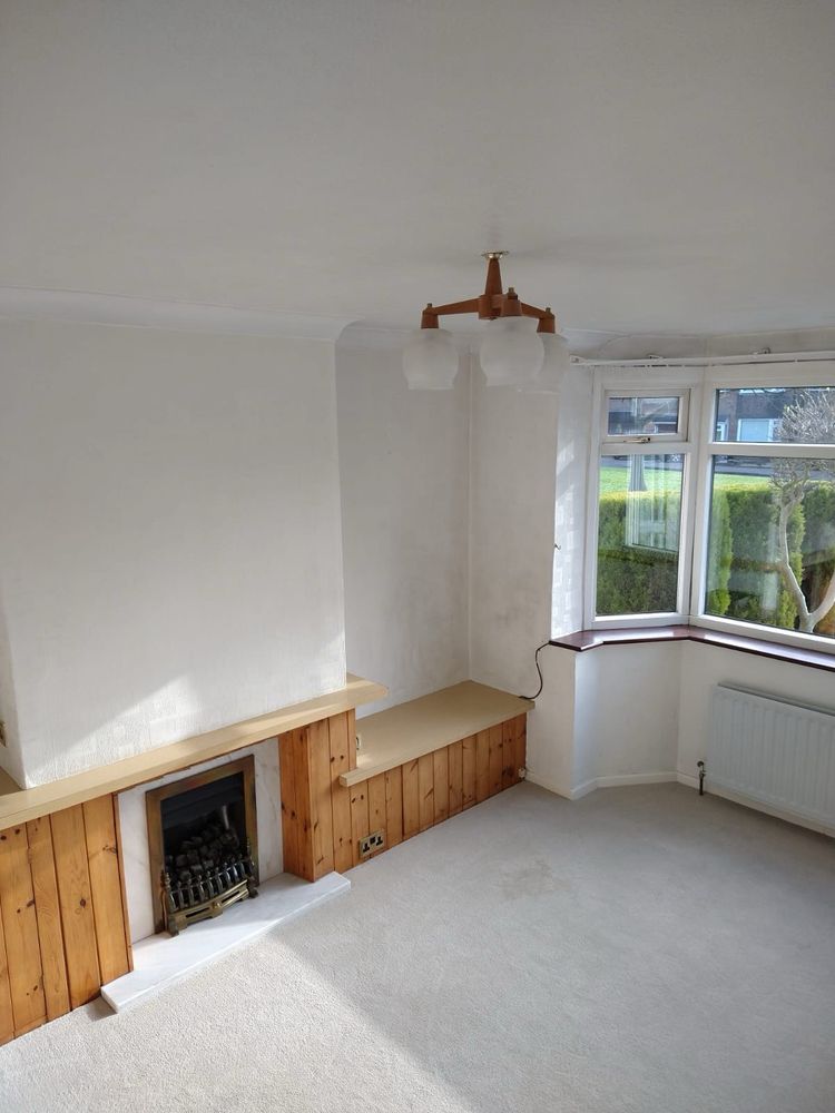 Plain white room with grubby walls and 1970s wooden light fitting, with orange stained built-in woodwork