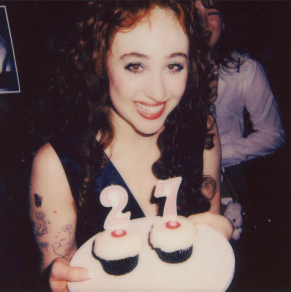 Photo of Chappell Roan at Chappell's 27th birthday party. She is holding 2 cupcakes that say 27.