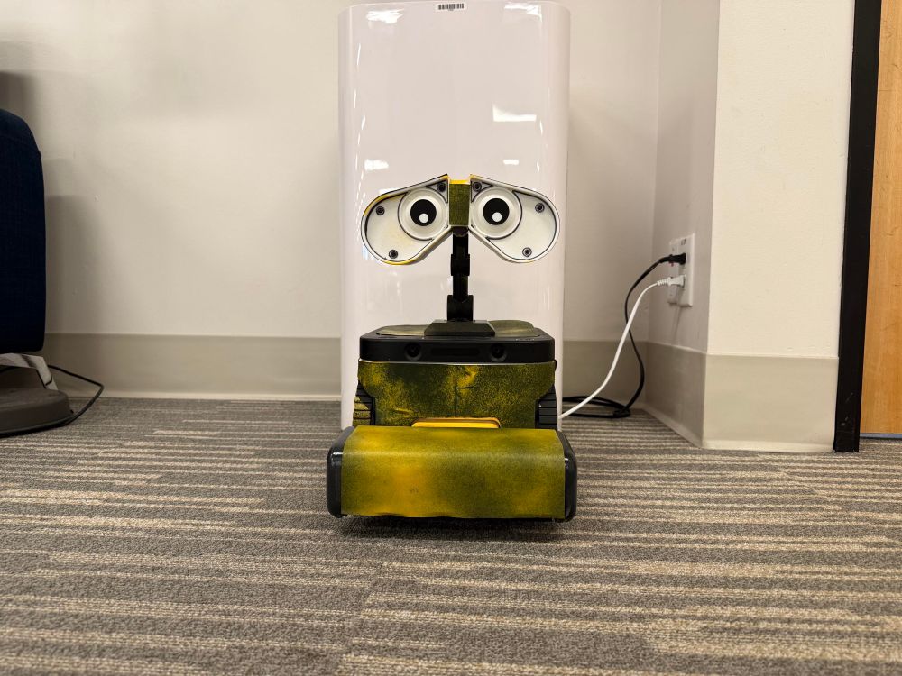 A yellow, boxy robot with a protruding vacuum head and large eyes that looks very similar to Wall-E