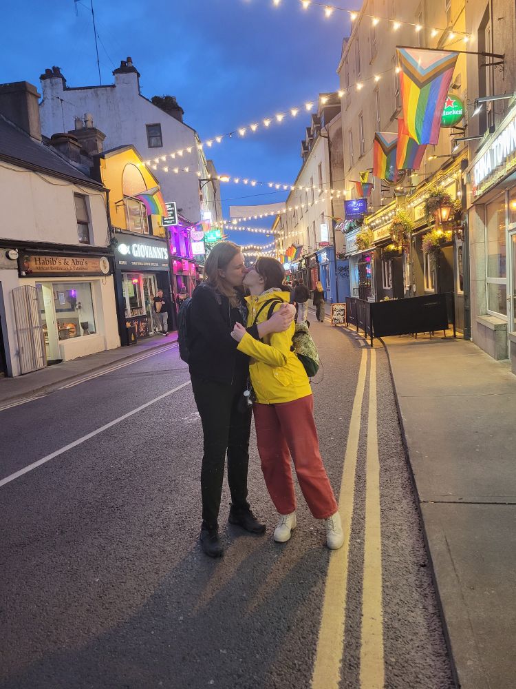 Zwei Leute in einer Straße voller Pride Progress Flaggen