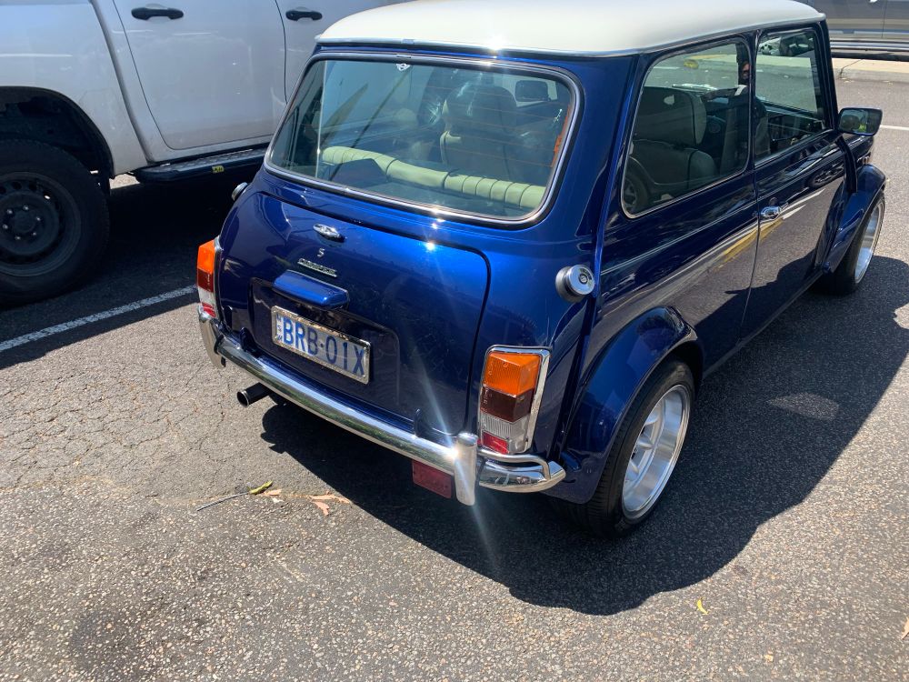 Read three-quarter view of a restored classic Mini Cooper S, in metallic blue 
