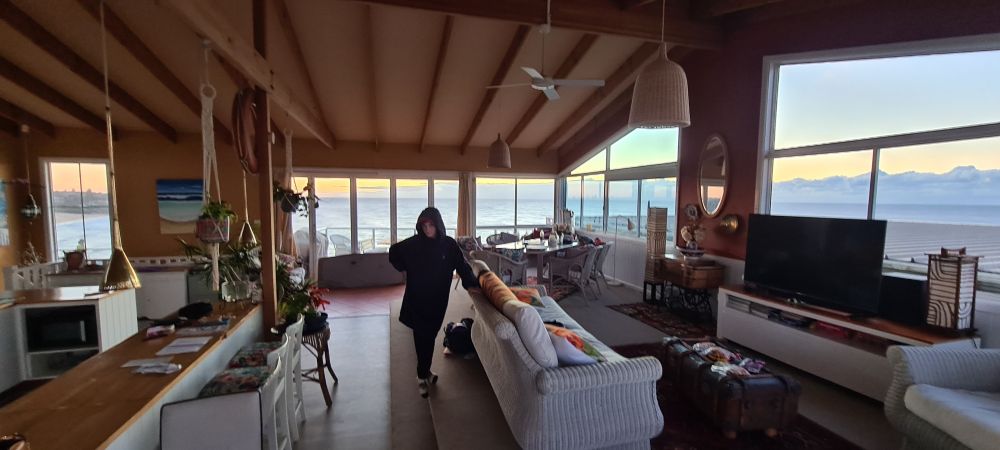 A jetlagged child haunting a spectacular house with panoramic ocean views, like a ghost in a hoodie.