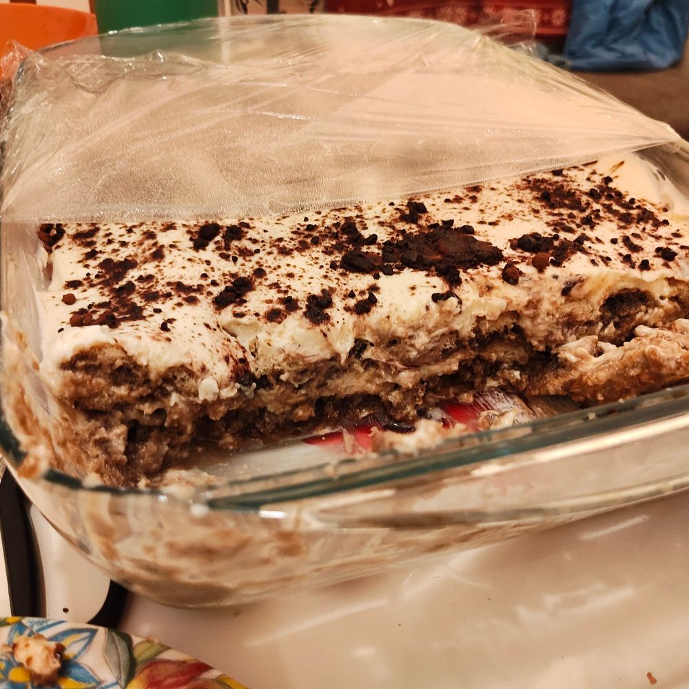 A homemade tiramisù viewed from the side, showing alternating layers of cream and soaked cookies