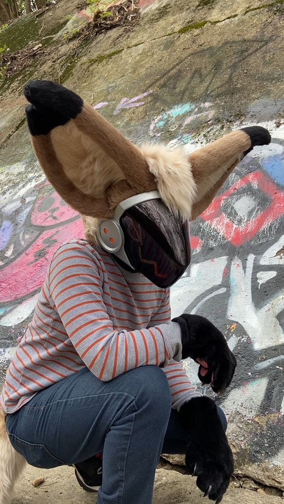 A protogen fursuit crouching down