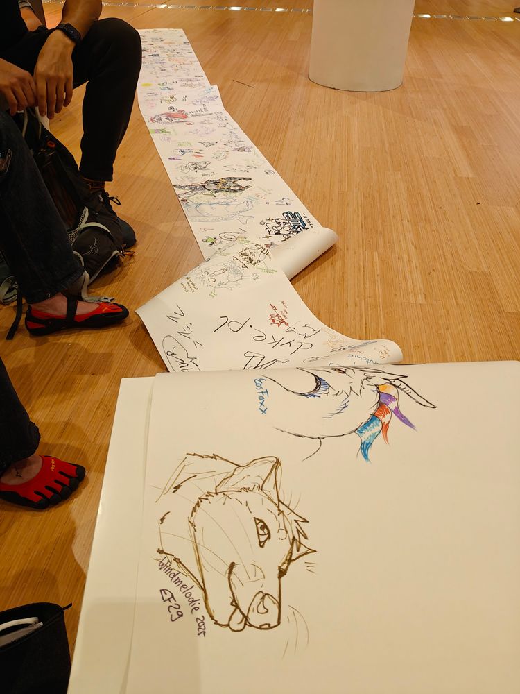 A long sheet of paper over the floor with a lot of scribbles, artworks and text on it